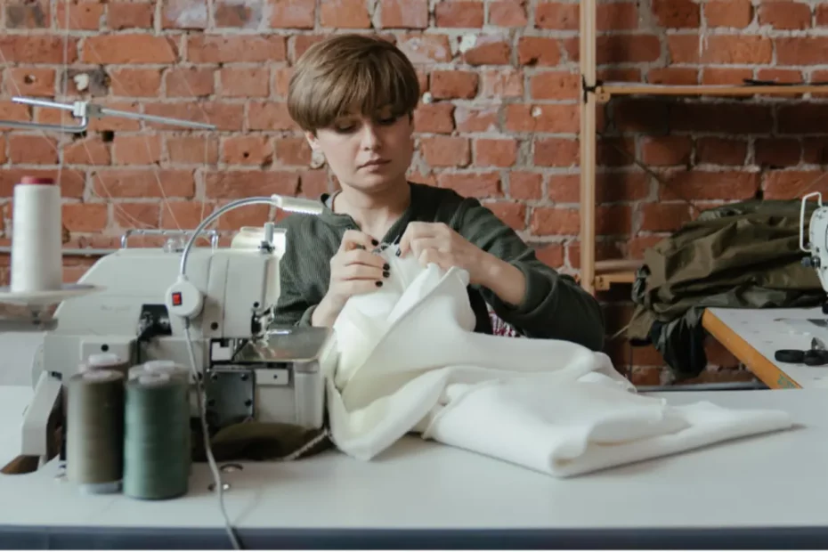 person hand sewing fabric near a sewing machine