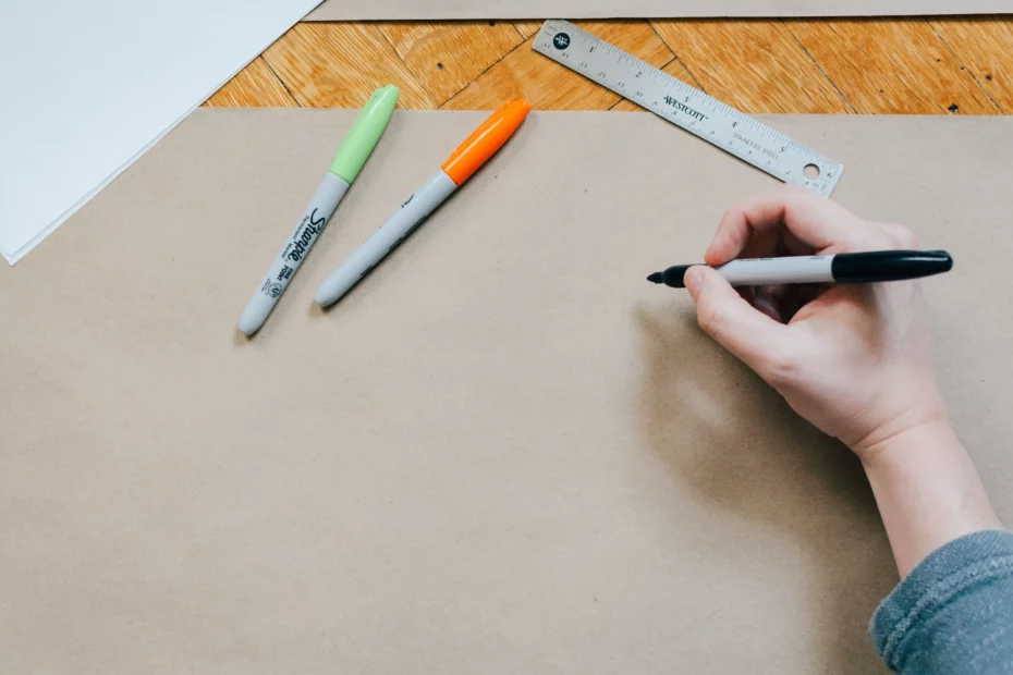 hand holding marker pen - about to draw on brown card