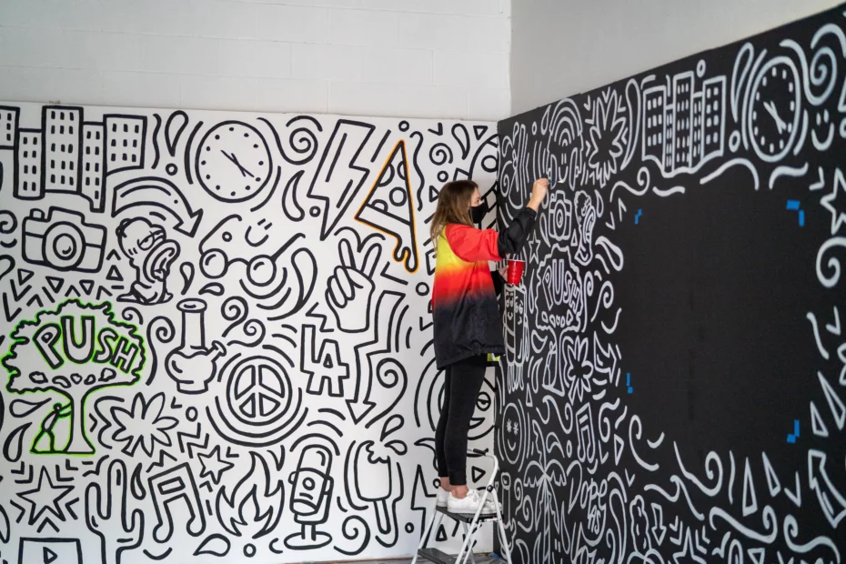 person painting artwork on black wall