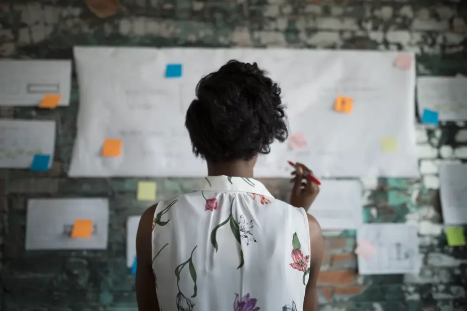 image of woman looking at brick wall with white sheets of paper and post it notes