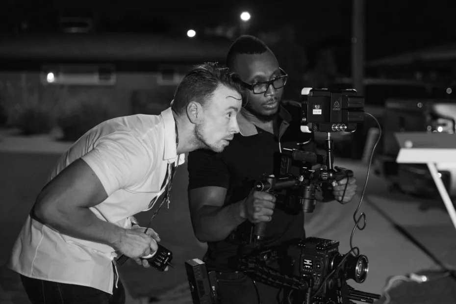 black and white photo of two men with a film camera